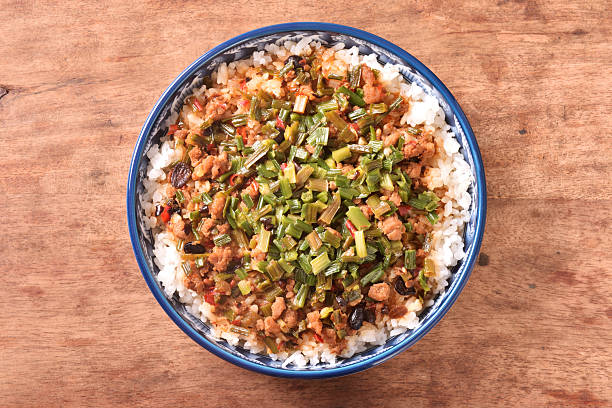 Fried minced pork with chive flower and black bean sauce over rice on wood table