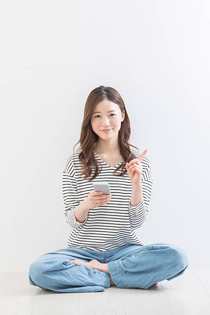 A woman sitting and holding a smartphone and pointing