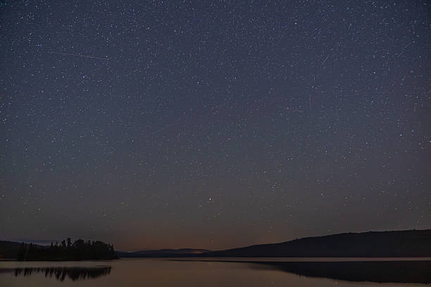 istock Stunning night sky filled with stars reflected on calm lake in serene wilderness. 2242482618