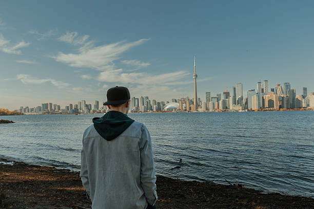istock Man standing by the waterfront looking at modern city skyline on a sunny day 2242490387