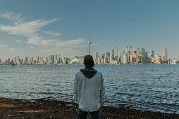 istock Man standing by the waterfront looking at modern city skyline on a sunny day 2242490388