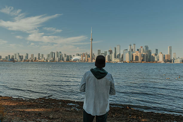 istock Man standing by the waterfront looking at modern city skyline on a sunny day 2242490389