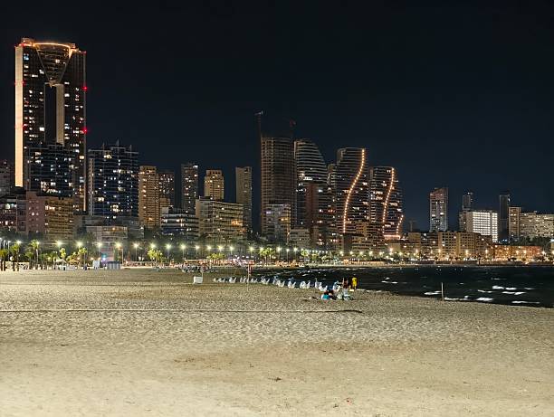 istock midnight city skyline with wet sand reflections, distant buildings soft surf and ambient 2242492133