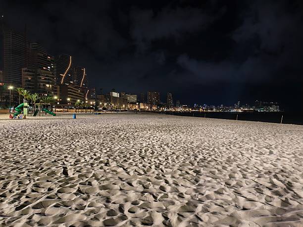 istock nighttime city stroll, tranquil night walk across sandy area beneath illuminated city skyline 2242494064
