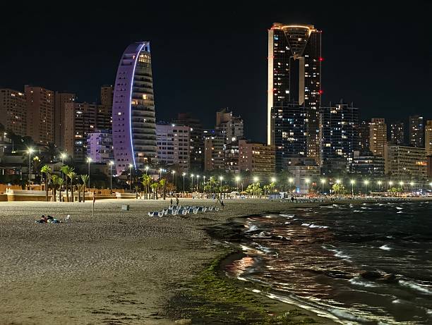 istock night beach panorama, serene nighttime seaside view with illuminated skyscrapers and gentle waves 2242494817