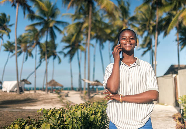 istock Smiling African woman talking on mobile phone at tropical beach 2242496736