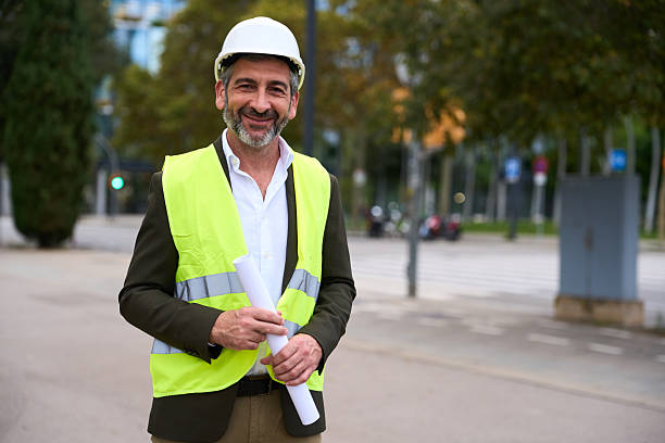 istock Smiling engineer wearing hard hat holding blueprint 2242499192