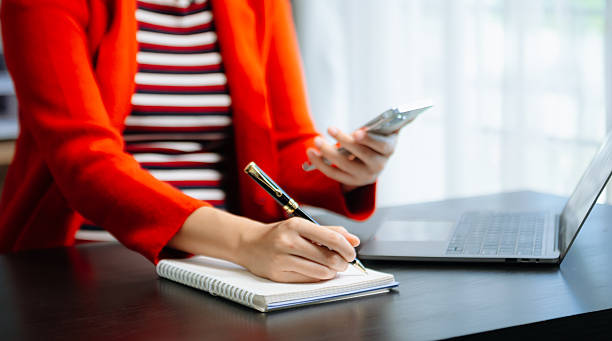 istock Close-up view of young professional businessman writing his idea concepts on notebook while working on his project at office 2242501635