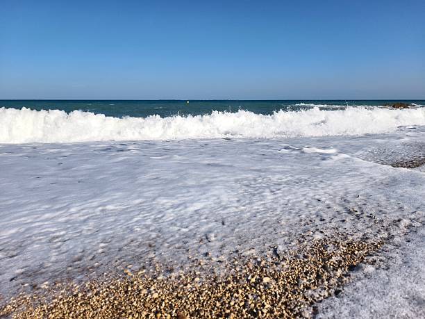 istock foamy waves over pebbled shore, dramatic ocean wave action over pebble beach environment captured 2242501818