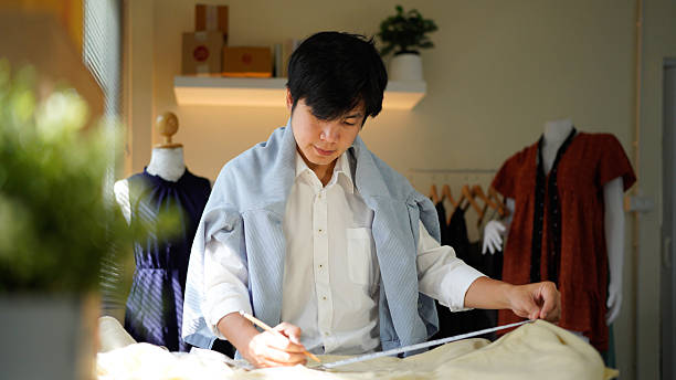 istock A man is doing some work on a piece of fabric as he is taking down measurements and trying his best to be accurate, 2242502045