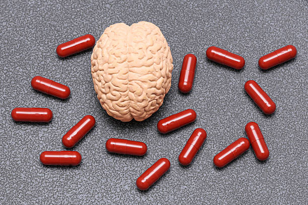 istock Artificial brain model surrounded by red capsules on gray background. Mental health and psychology concept. 2242503005