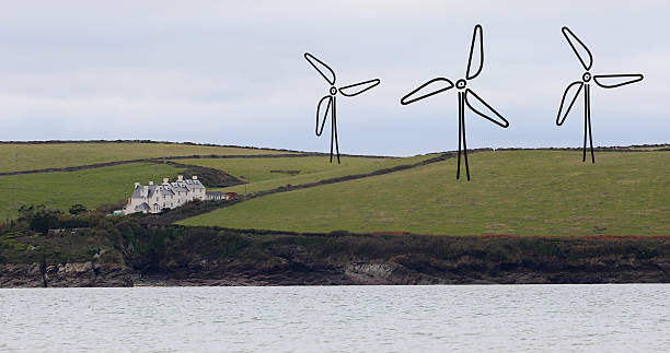 Filling up the gap / renewable energy concept: Three hand-drawn wind turbines on a hill by the sea near Padstow in Cornwall.
