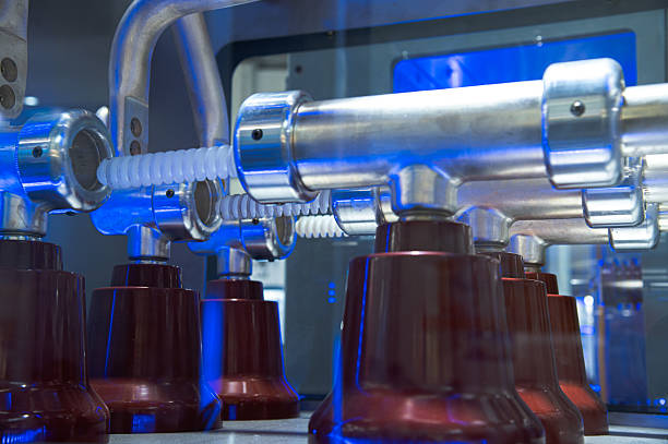 Automated industrial machine filling and capping small plastic containers with blue light