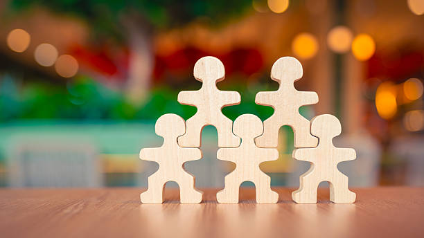 istock Wooden human figures arranged in pyramid shape on table, symbolizing teamwork, leadership, support, unity, and collaboration. Perfect for business, HR, and organizational concept visuals. 2242505900