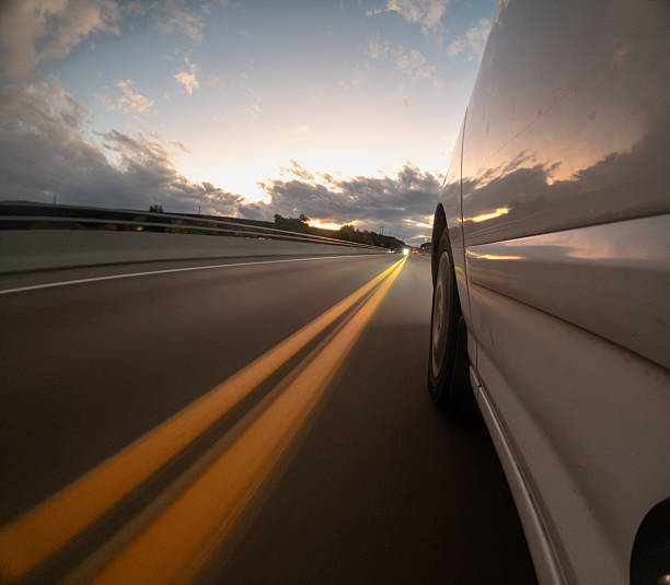 istock A car is driving down a road with a sunset in the background 2242508346