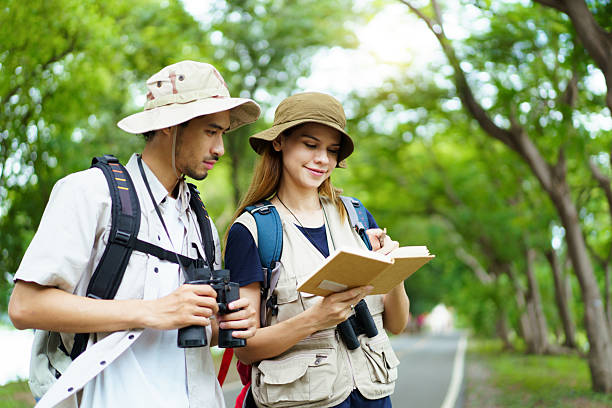 istock Asian man and woman hikers with binoculars birdwatching and taking notes in nature 2242509145