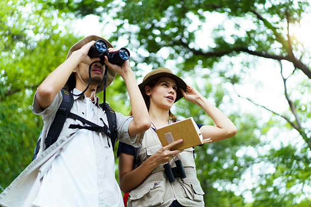 istock Asian man and woman hikers with binoculars birdwatching and taking notes in nature 2242509152