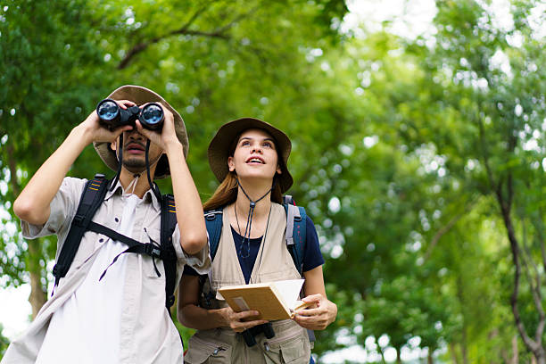 istock Asian man and woman hikers with binoculars birdwatching and taking notes in nature 2242509154