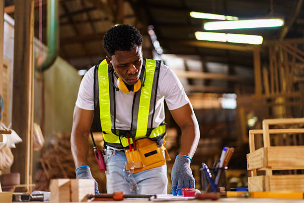 istock Black carpenter working with wood design plans in workshop 2242509199
