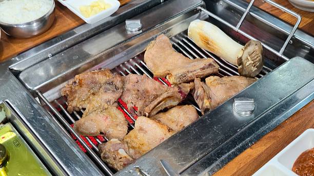 This is a scene of bone-in short ribs and beef tongue , a popular BBQ dish, being grilled on a hot plate. You can almost hear the sizzling sound from the image.