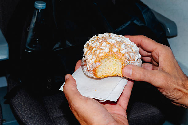 closeup of a man holding a brioche con granella di zucchero, a traditional Italian pastry topped with sugar crystals, inside a train or bus during his journey