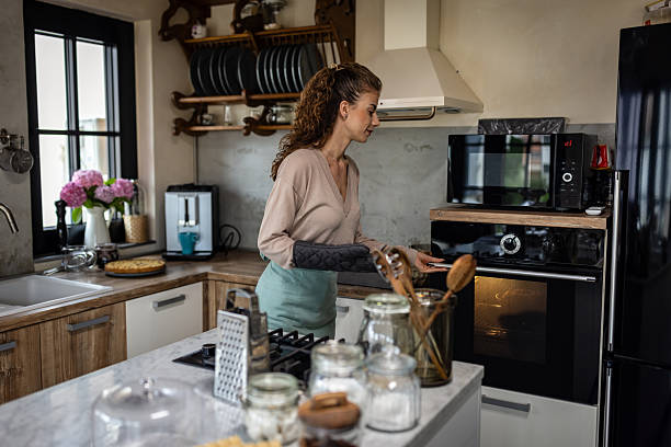 istock Woman Baking in Modern Kitchen Using Oven and Microwave, Cozy Home Cooking Scene 2242518290