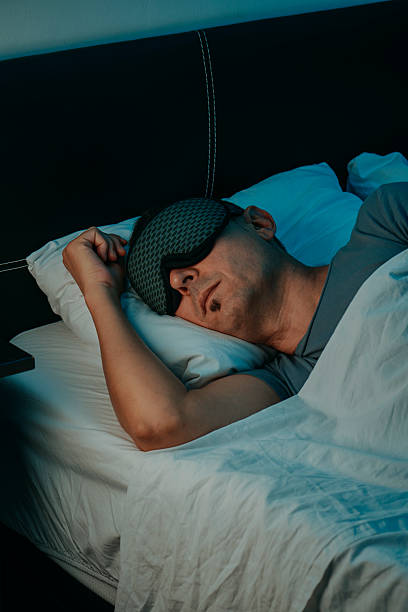 istock a man lying on his side with a sleep mask in bed 2242518438