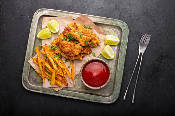 istock British Traditional Fish and chips with lime and sauce on black background top view 2242519514