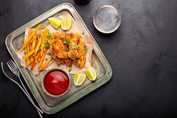 istock British Traditional Fish and chips with lime, sauce and cold beer on black background top view copy space for text 2242519562