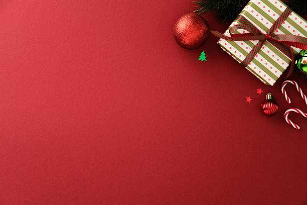 istock Christmas gift box with candy cane, bauble and evergreen branch on red background. Festive flat lay for holiday greeting, winter celebration and seasonal design 2242520044