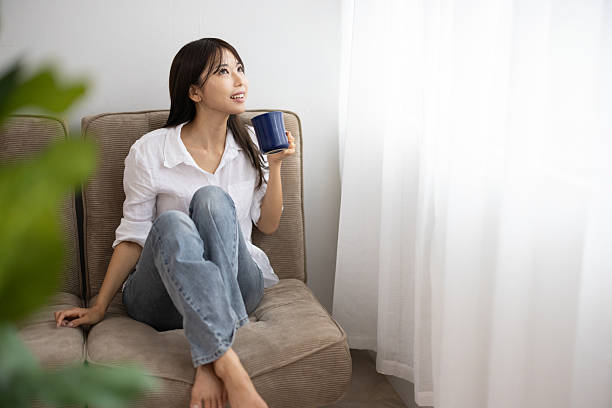 istock Young Woman Smiling with a Mug by the Window 2242520134