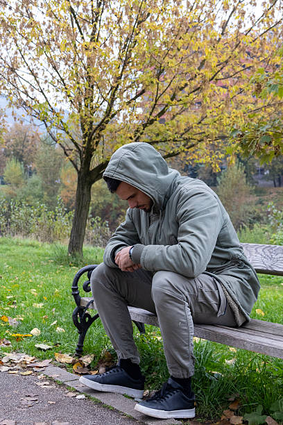 Man enjoying a peaceful autumn day in the park, sitting on a bench and walking among fallen leaves. Warm colors, seasonal atmosphere, and natural light create a calm and reflective fall mood.