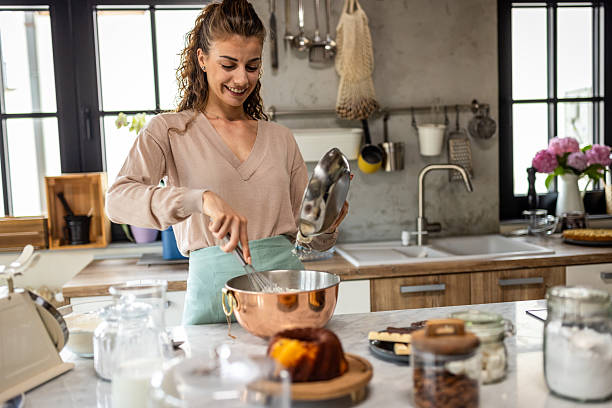 istock Happy Home Baker Stirs Batter in a Modern Kitchen With Copper Mixing Bowl and Fresh Pastries 2242521877