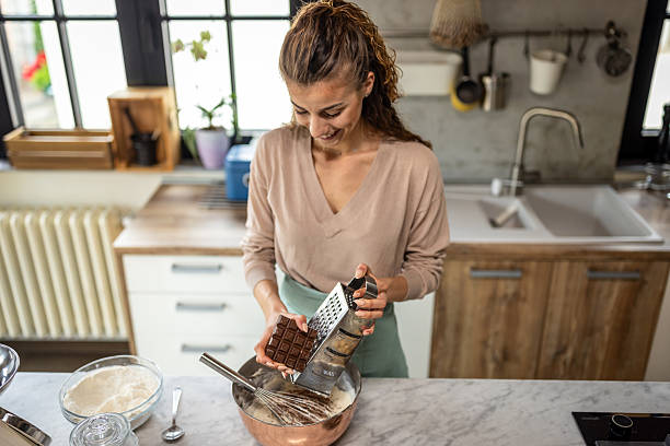 istock Woman In Kitchen Grating Chocolate Into Bowl While Mixing Batter For Homemade Baking 2242522046