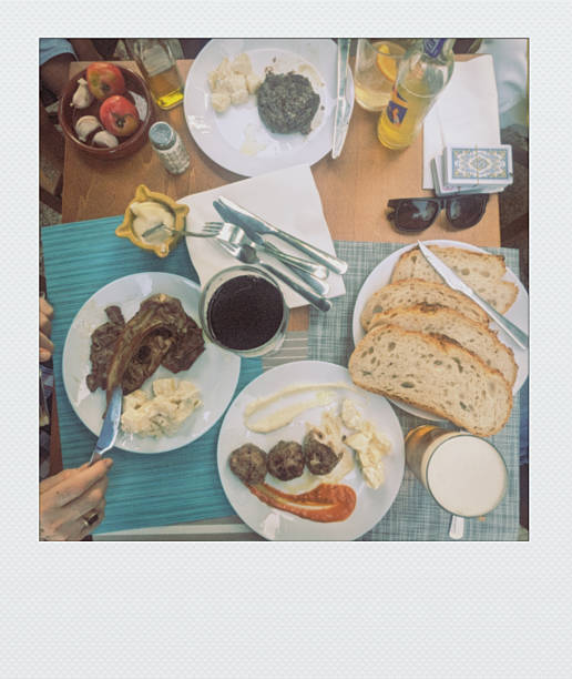 A rustic plate of sliced jamón, assorted cheeses, and crusty bread is served with a glass of beer, ready for a casual meal.