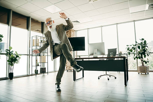 istock Elderly businessman energetically dancing inside modern office space with contemporary decor, embracing fun and confidence 2242525899