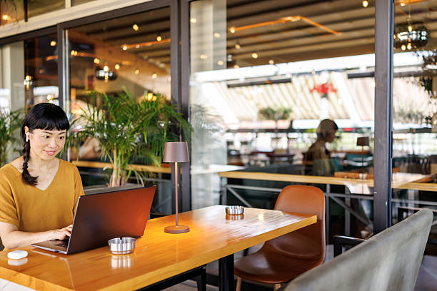 Japanese mid-adult female freelancer calmly working on her laptop in a contemporary coffee shop