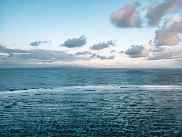 Deep blue ocean water moving with gentle waves under a beautiful cloudscape and horizon in Badung, Bali