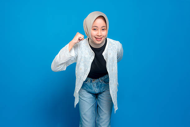 istock Cheerful young woman wearing hijab smiling confidently while making a dynamic pose with a clenched fist, expressing motivation, determination, and positive energy. 2242529188