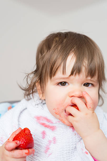 istock Baby girl eating strawberries 2242530309