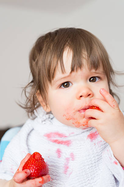 istock Baby girl eating strawberries 2242530333