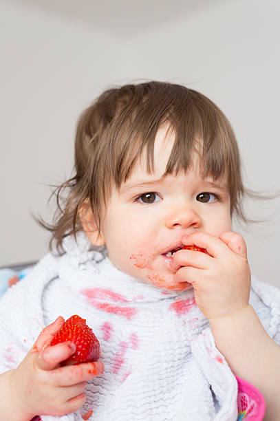 istock Baby girl eating strawberries 2242530374