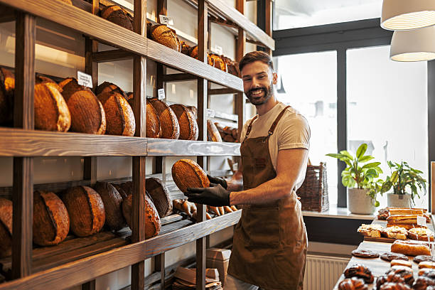 istock Handsome Man Wearing Apron Holding Fresh Bread Loaf 2242534846