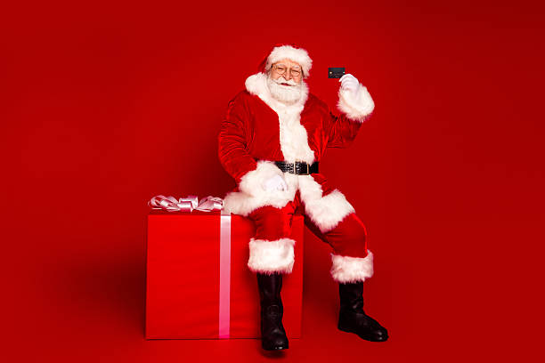 istock Santa Claus sits on a large gift box taking a selfie with a red background celebrating Christmas and the holiday season with gift ribbon and festive vibe 2242535001