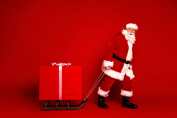 istock Santa Claus pulls a sleigh with a large red gift against a bright red background creating a festive holiday scene full of joy and celebration 2242535039