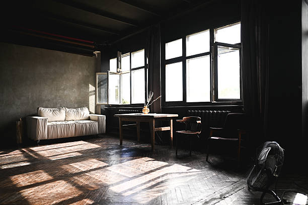 Sunlight illuminating a vintage room with a sofa and wooden floors, creating dramatic shadows