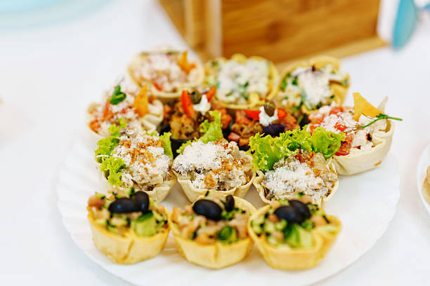 A platter filled with various savory tarts showcases a mix of fresh ingredients, including vegetables and herbs. These delicious bites are perfect for a festive gathering or a casual meal.