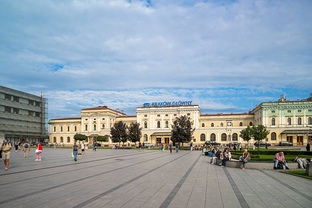 12 September 2025 Krakow, Poland. People walking near the ornate facade of a classic European railway station in Krakow, Poland, on a clear day with vibrant colors and dynamic city atmosphere.