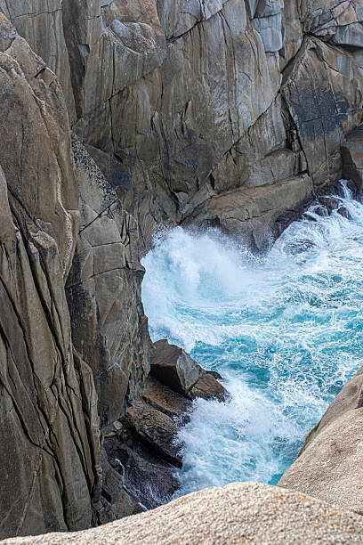 istock Blue waves crashing against the rocky cliffs 2242550376