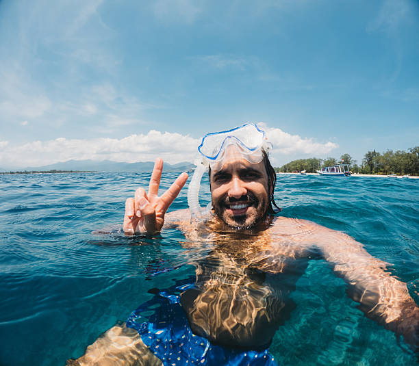 istock Man snorkeling in ocean making peace sign selfie 2242550757